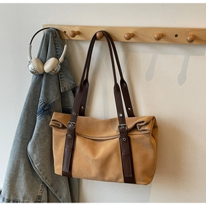 Detailed close-up of khaki tote bag with dark brown leather straps on a wooden hook
