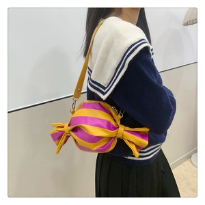 Detail of candy-shaped striped PU leather shoulder bag worn over the shoulder