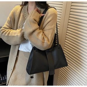 Detail of black pebbled leather tote bag worn as a stylish underarm shoulder bag