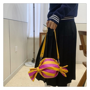 Detail of candy-shaped shoulder bag featuring vibrant pink and yellow stripes with silver hooks