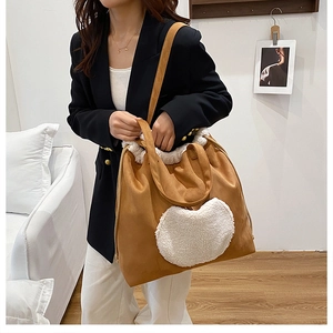 Detail view of heart-shaped faux fur patch on brown suede tote bag with fleece trim
