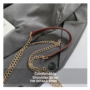 Detail eines bequemen braunen Wildleder-Schultergurts mit eleganter goldener Metallkette