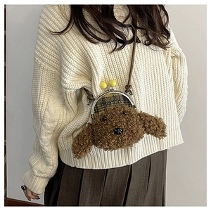 Détail d'un sac bandoulière chien en peluche marron avec fermoir doré sur un pull