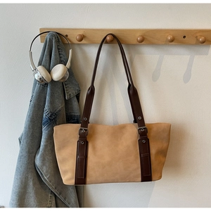 Detail of large tote bag with beige suede texture and brown leather strap on a wall hook