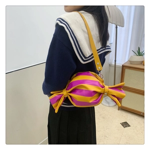 Close-up of candy-shaped crossbody bag featuring pink and yellow stripes and leather strap