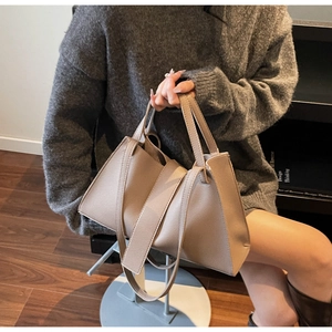 Detail of taupe textured leather handbag with elegant handle and draped decorative strap
