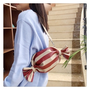 Detail of creative candy-shaped crossbody bag featuring red and white vertical stripes