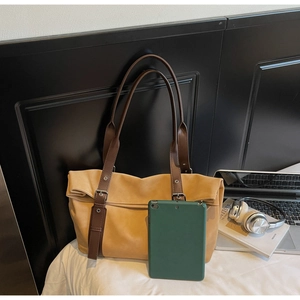 Close-up of a large ochre tote bag with brown straps and silver buckles for daily commute
