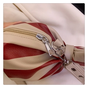 Close-up of red and beige striped faux leather shoulder bag with silver metal hardware