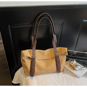 Detail of camel tote bag with brown straps, metallic buckles, and a minimalist style