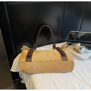 Macro view of mustard suede tote bag detail with dark brown handles and elegant side pleats