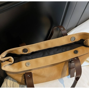 Detail view of mustard tote bag with interior black lining and magnetic silver buckles