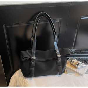 Close-up of black tote bag with silver metal eyelets and leather straps on canvas material