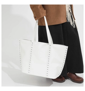 Detailed view of a white large tote bag with silver rivets held by a model