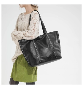 Detail of black tote bag featuring silver rivet studs and textured synthetic leather