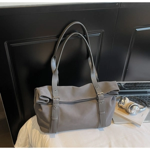 Detail of grey tote bag featuring nylon fabric, buckle straps and sleek metal hardware