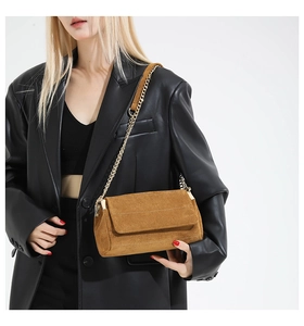 Detailansicht braune Wildleder-Umhängetasche mit goldener Kette an einem Model