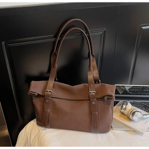 Detail of dark brown tote bag with silver buckles and matte synthetic leather texture
