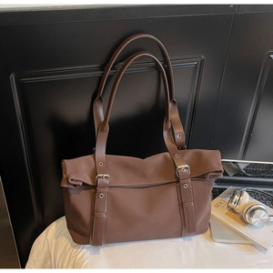 Close-up of a large brown leather tote bag with silver buckle details in an office setting