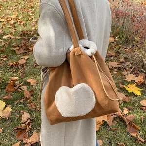 Retro brown suede tote bag with white plush heart and drawstring in autumn setting