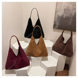 Detailed shot of four suede hobo bags in assorted colors with decorative metal rivets