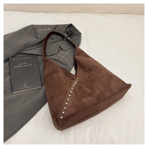 Macro shot of brown suede hobo bag with vintage silver rivet details and leather strap