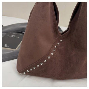 Detail of dark brown suede shoulder bag featuring retro silver metallic rivet accents