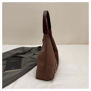 Detail view of brown suede shoulder bag with silver rivet studs and leather strap