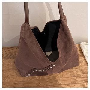 Detailed view of dark brown suede hobo bag with silver studs on wooden surface