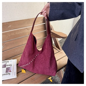 Detail of burgundy suede shoulder bag with silver rivet accents and leather handle