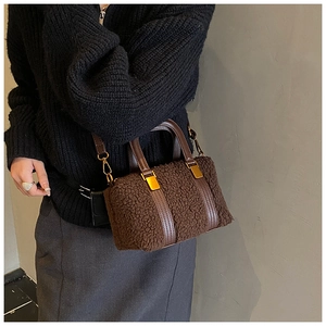 Detail of a plush brown Boston bag featuring faux leather handles and golden metal zippers