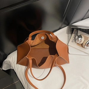 Brown lychee grain leather tote bag shown in a lifestyle scene with laptop and book
