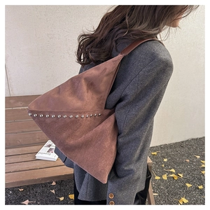 Detailed side view of brown matte suede hobo bag with silver rivet studs in autumn setting