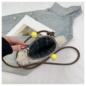Détail du sac bandoulière en peluche avec fermoirs boules jaunes et doublure à carreaux