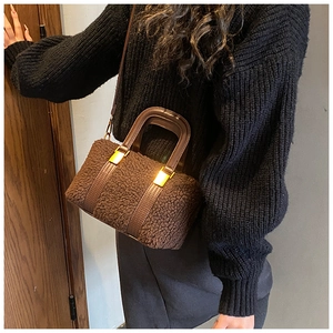 Detail of plush faux shearling bag featuring brown leather straps and gold metal buckle