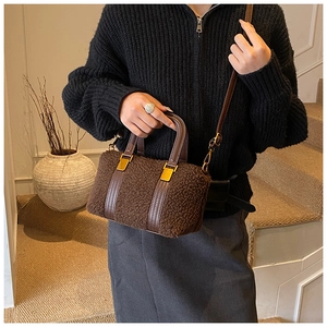 Detail of dark brown plush fleece Boston bag with golden hardware and leather handles