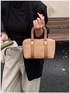 Detail of camel plush Boston bag featuring brown leather straps and gold metal lock hardware