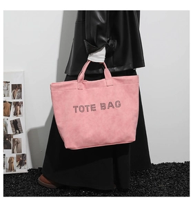 Fashionable pink suede tote bag worn by model with minimalist industrial style background