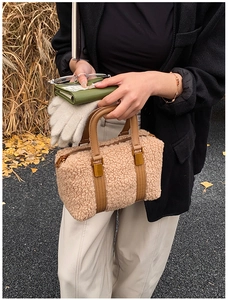 Detail of plush faux lambskin Boston bag featuring brown leather handles and gold zippers