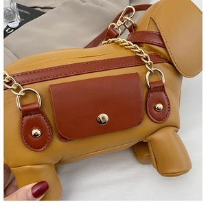 Detail shot of the dachshund dog-shaped shoulder bag featuring stitching and golden chains