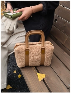 Detail of beige fleece Boston bag with brown leather handles and golden zippers