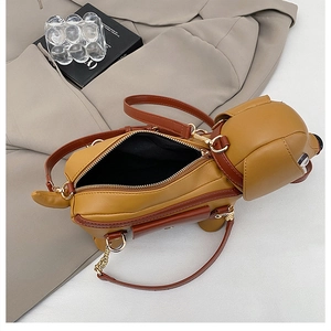 Detail of cute puppy-shaped crossbody bag with gold zipper closure and chain strap