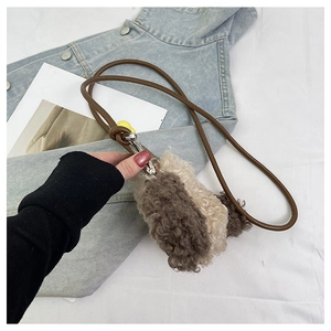 Détail du sac bandoulière en peluche bicolore avec bandoulière en cuir et boucle métal