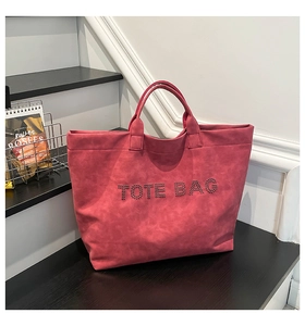 Detail of hot-pink suede tote bag with studded TOTE BAG text on a minimal staircase