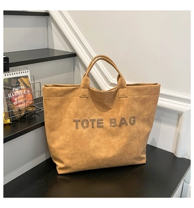 Detail of camel PU leather tote bag featuring rivet studs spelling out TOTE BAG text
