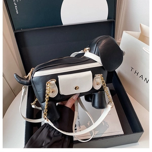 Detail of dachshund puppy shaped crossbody bag with gold chain and black white contrast