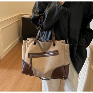 Detail view of khaki canvas tote with contrast leather stitching and zipper outer pocket