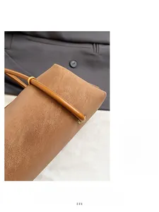 Gros plan du sac baguette en cuir marron avec anneaux dorés et détails de couture