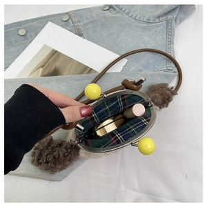Détail du sac à bandoulière en peluche avec doublure à carreaux et espace intérieur