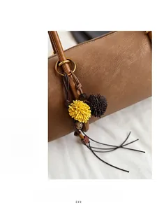 Détail des charms floraux décoratifs sur un sac à bandoulière en daim marron